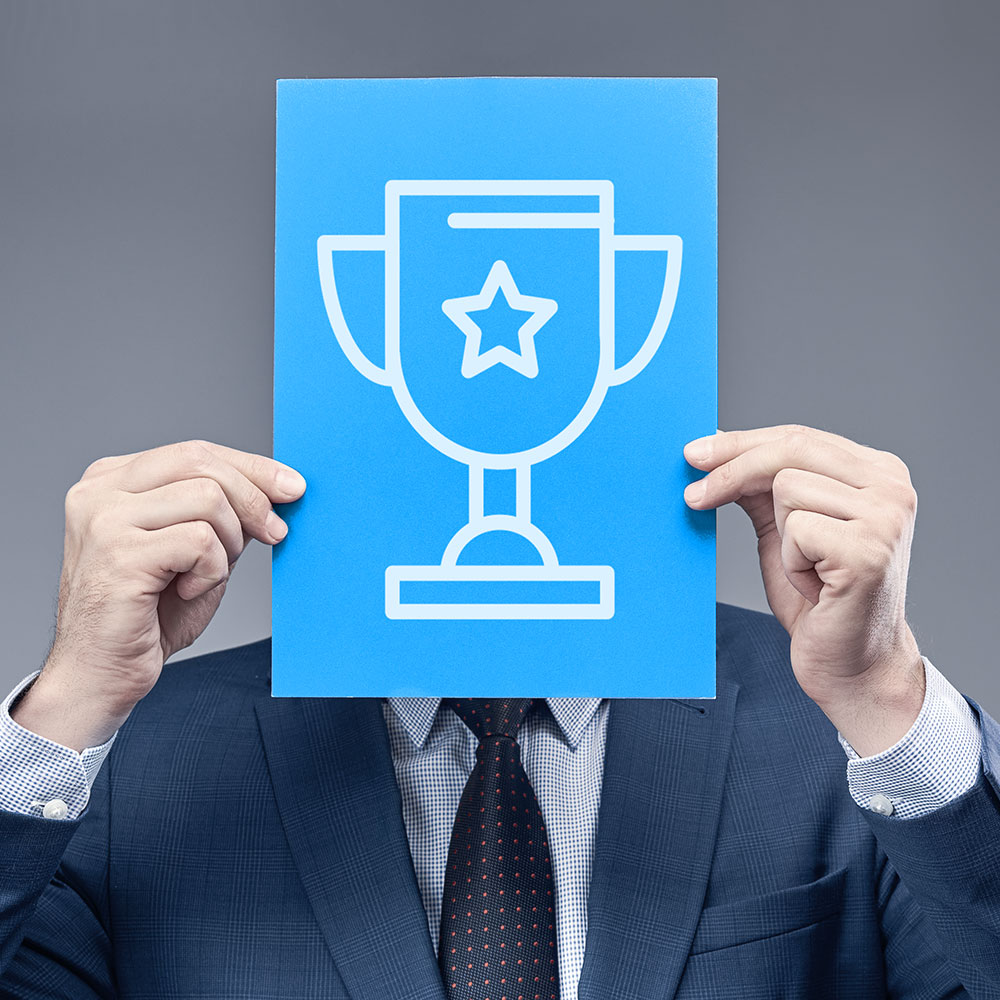 Imagen de una persona sujetando un cartel con el símbolo de una copa como premio