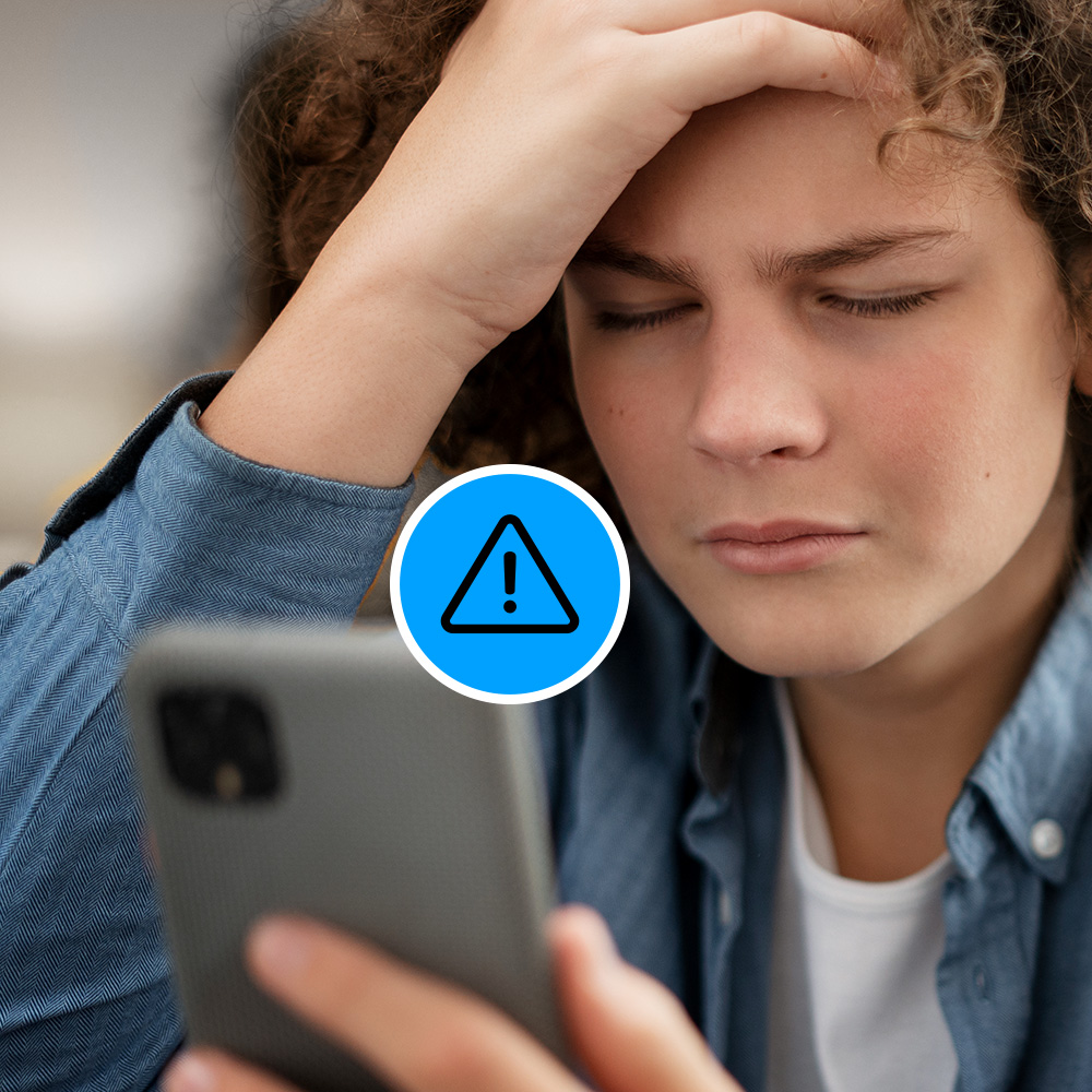 Person looking at a smartphone with a concerned expression, hand on forehead. A warning icon is displayed on the image.