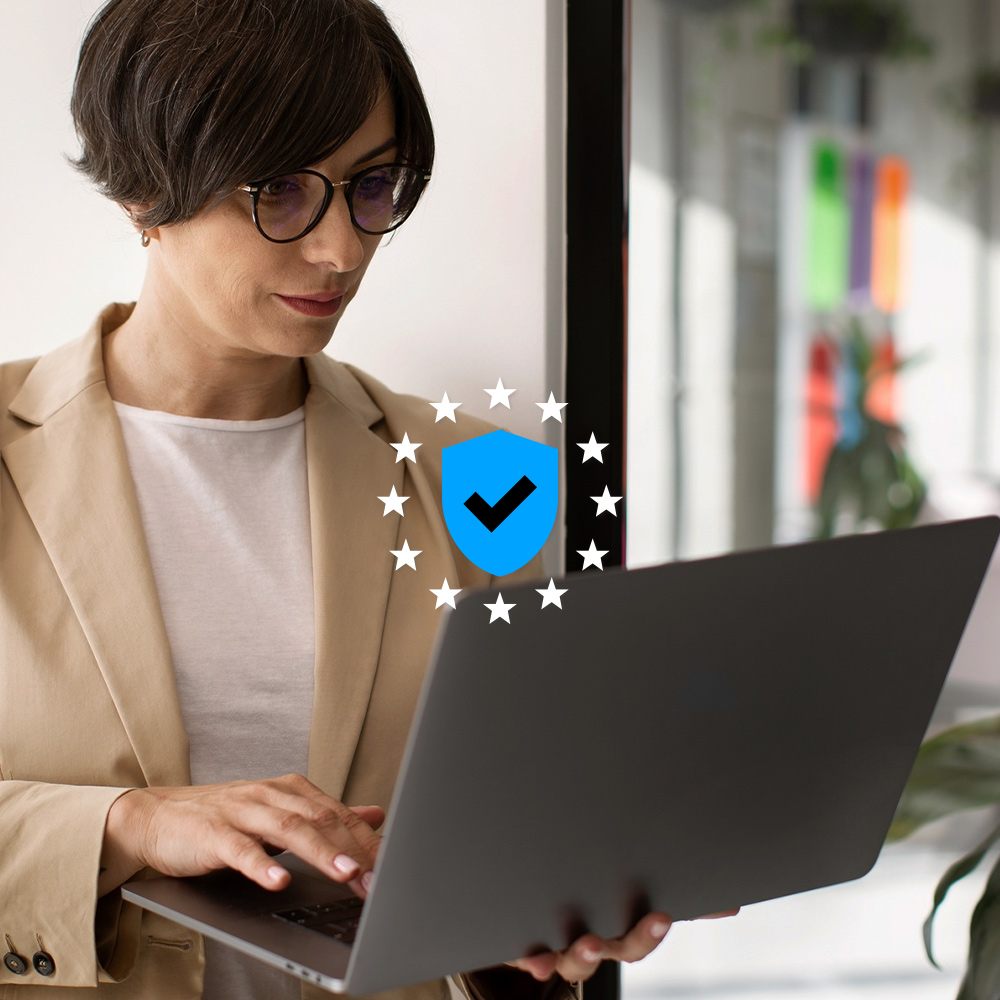 Image with a woman and a laptop and on top the icon of a privacy shield and some stars surrounding it
